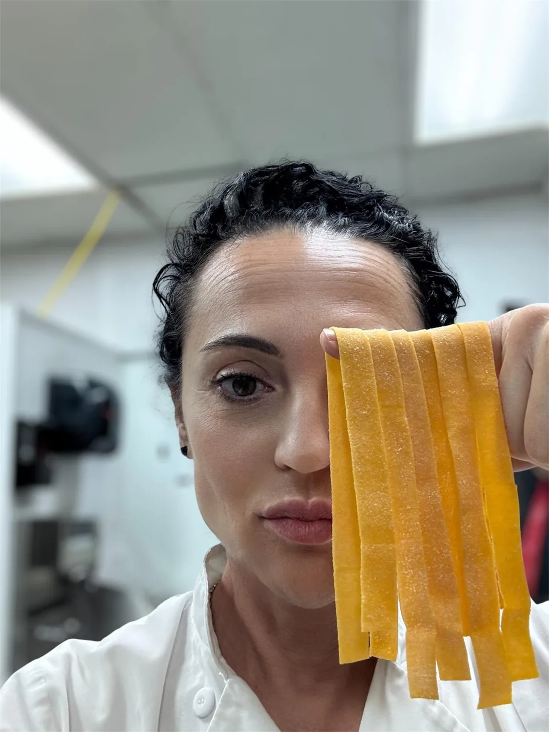 Chef Laura Migliorini holding fresh handmade pasta in the Milano kitchen